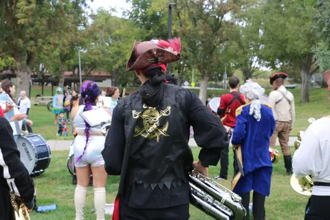 A busy crowd of costumed band members seen mostly from behind.