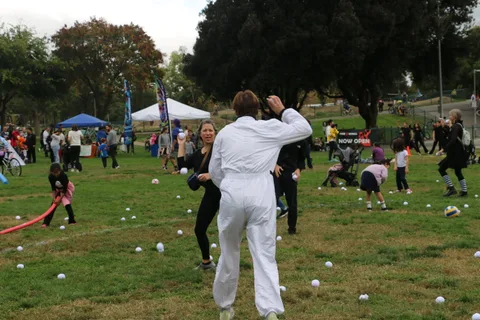 A person in white throws a ball across the lawn game field.
