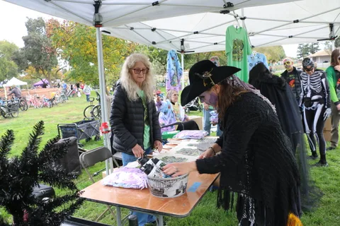 Two costumed women organize festival decorations at a table.