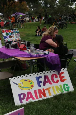 A colorful sign for face painting stands on the grass.