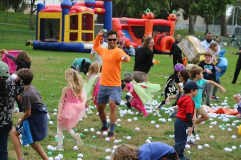 Kids run across the grass near the bounce houses.