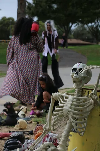 Hands reach into a candy pile beside skeleton props.
