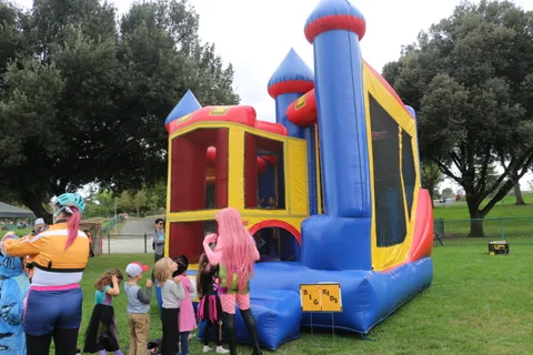 Children line up to enter a colorful inflatable bounce house.