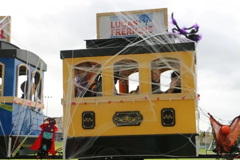 A decorated yellow parade cart sits parked near the playground.