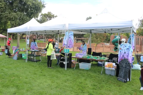 Volunteers set up tables under a white tent booth at the festival.