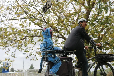 A cyclist in a blue jumpsuit performs a trick on a decorated bike.