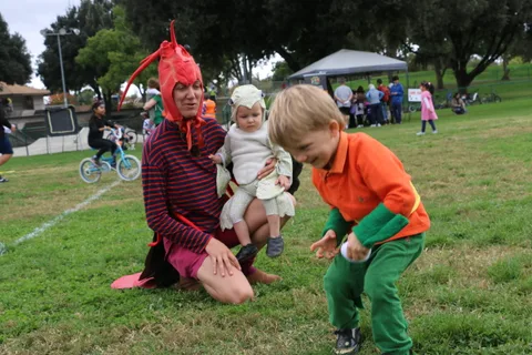 A boy interacts gently with his baby sister dressed as a lamb.