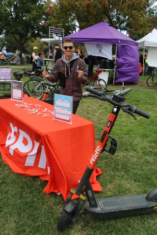 A man in sunglasses smiles near a purple tent with bikes nearby.