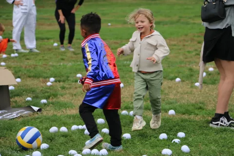 A boy in a blue superhero costume runs and plays with a friend.