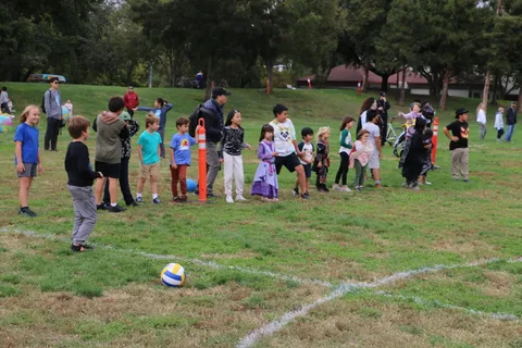 Costumed kids gather on the grass to play a ball-toss game.