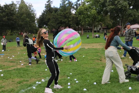 A woman in a skeleton costume reaches for a ball on the festival field.