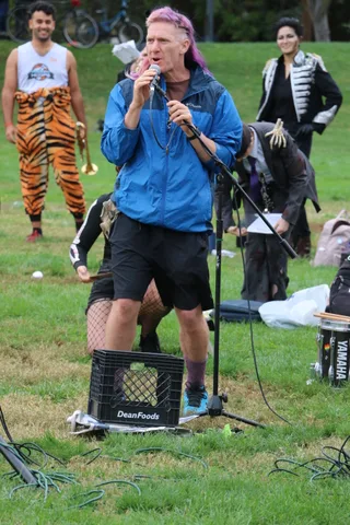 Dancers in tiger-striped leggings move in front of a DJ setup, cropped at the waist.