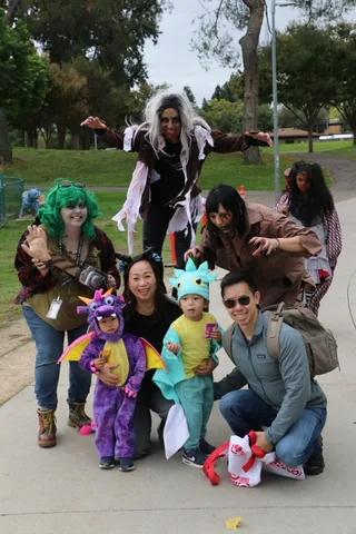 A smiling family portrait with children in dragon and dinosaur costumes.