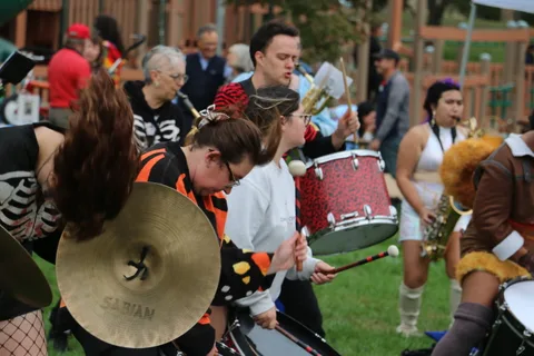 A cymbal player clashes her cymbals mid-motion in a sparkly costume.