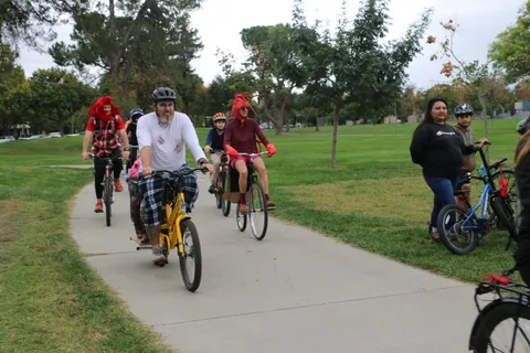 Riders in plaid pants pedal down the tree-lined path.