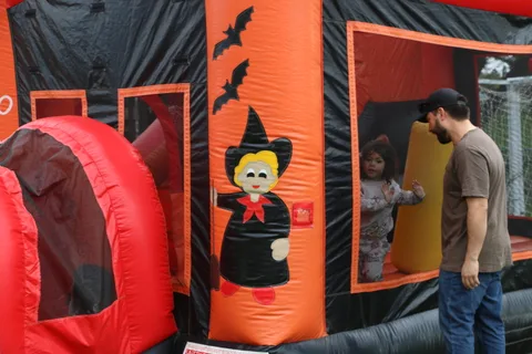 A painted witch and vampire decorate the entrance of an inflatable Halloween attraction.