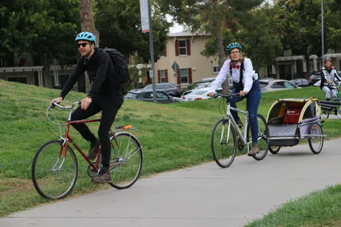 Two cyclists ride together along a quiet stretch of path.