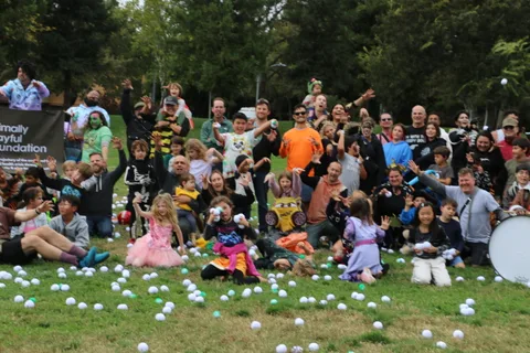 A large crowd of costumed festival-goers pose together for a group photo on the grass.