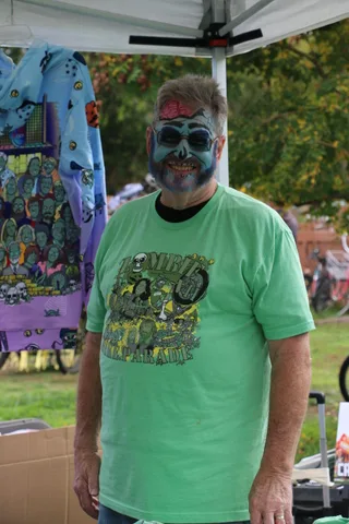 A close view of a person's green festival shirt with bicycles blurred behind.