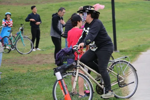 An adult and child ride bikes together along the path.