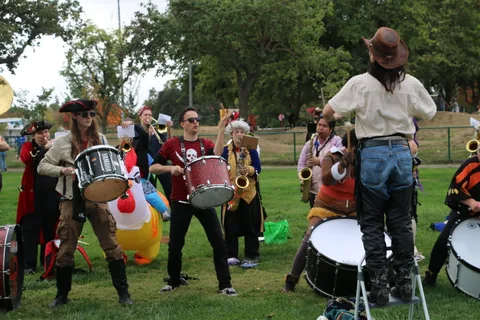 A pirate-costumed drum line plays together with an inflatable chicken nearby.