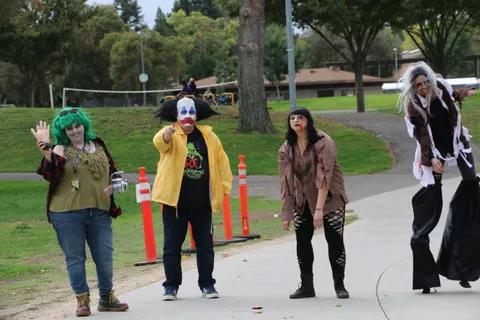 A clown, zombie performer, and stilt walker gather on the path.