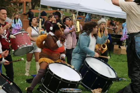 Drummers and horn players perform together near the festival tents.