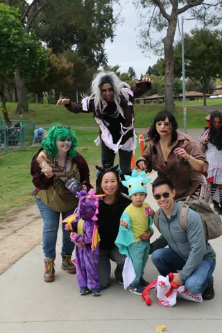 A zombie performer reaches toward the camera as two others stand behind her.