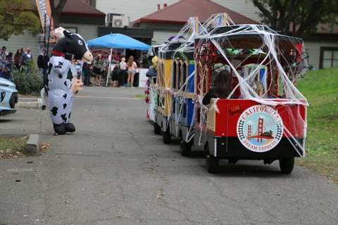 Decorated train cars line the path near a blue vendor tent.