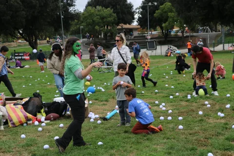 A woman bends to pick up a ball while a boy watches nearby.