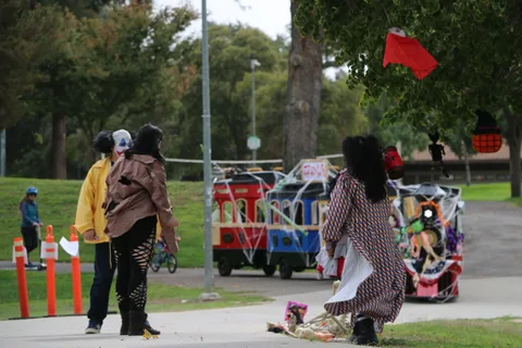A small red flag flies above a park path as costumed figures walk in the distance.