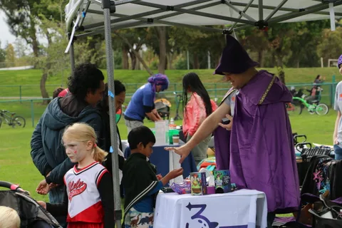 A costumed volunteer hands a treat to a young girl at the booth.