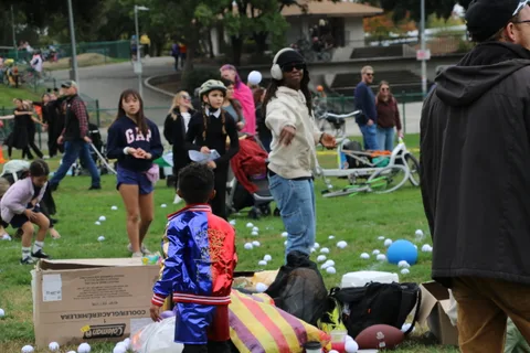 A small group gathers near cardboard boxes and balloons at the festival edge.
