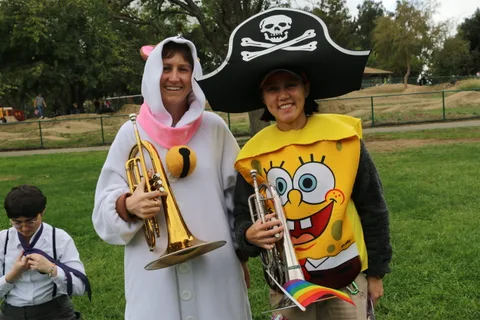 Two women in cartoon sponge costumes pose again with their trumpets.