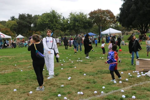 A person in a white astronaut costume plays a lawn game with children.