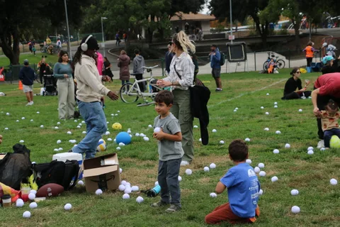 Children and an adult stand among scattered balls at the festival lawn game.