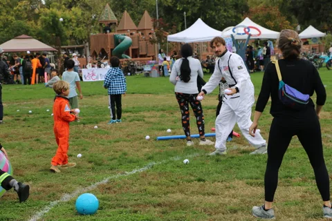 Children and adults gather with pool noodles during the lawn game.