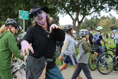 A woman in zombie face paint reaches toward the camera with a dramatic expression.