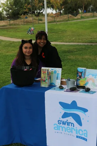 A close view of a Swim America sponsor table with no person clearly in frame.