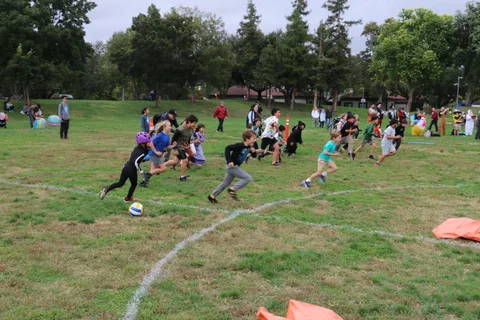 Kids run and scatter across the grass field during the game.