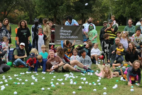 A large crowd of costumed festival participants pose together on the grass.