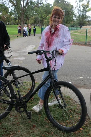 A rider in bloodied zombie bride makeup smiles at the camera while sitting on her bike.