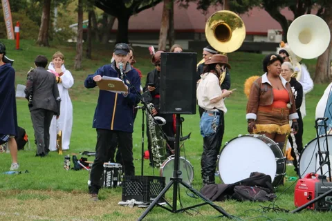 Band members in tiger and chicken-feather costumes perform on brass instruments.