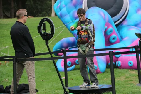 A boy plays a target game in front of a giant inflatable caterpillar sculpture.