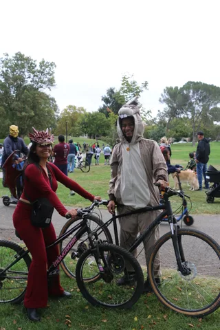 A wide, hazy view of costumed riders on the park path.