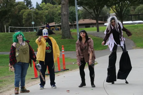 A group of costumed performers gathers along the park path.