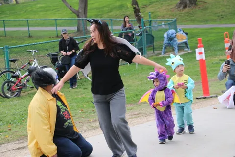A zombie performer playfully reaches for a child in a dragon costume.