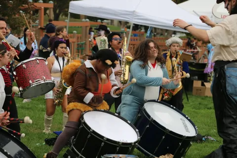 The costumed drum line performs beneath the festival tents.