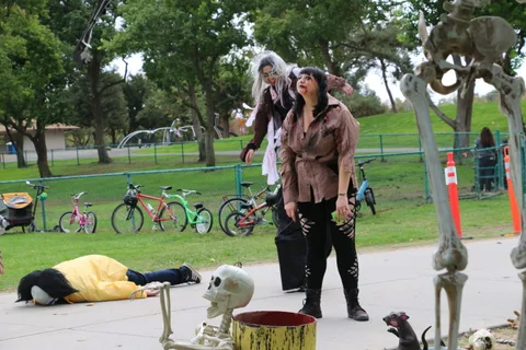 Zombie performers gather beside cemetery-themed decorations.