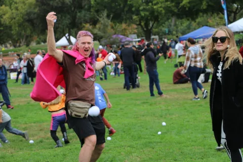 A man in a pink cape cheers with arms raised during the festival.